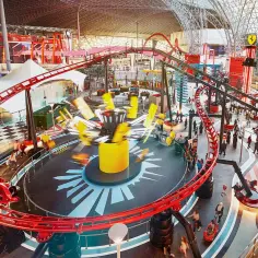 Wesołe miasteczko Ferrari World w Dubaju z kolejką górską i karuzelami w akcji.