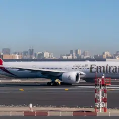 Samolot Emirates na płycie lotniska, w tle panorama Dubaju. Zastanawiasz się, ile trwa lot Warszawa Dubaj?