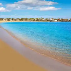 Piękna plaża z turkusową wodą i palmami. Zastanawiasz się, ile trwa lot na Wyspy Kanaryjskie z Warszawy?