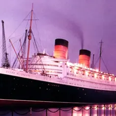 Majestatyczny statek Queen Elizabeth cumuje w porcie o zmierzchu, z dymem unoszącym się z kominów.