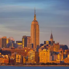 Zachód słońca nad Manhattanem. Widać Empire State Building i Chrysler Building. Zastanawiasz się, ile km do Nowego Jorku?