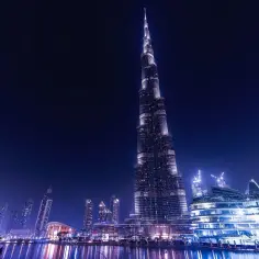 Nocny widok na Burdż Chalifa, symbol Dubaju, jaki to kraj, z odbiciem w wodzie.