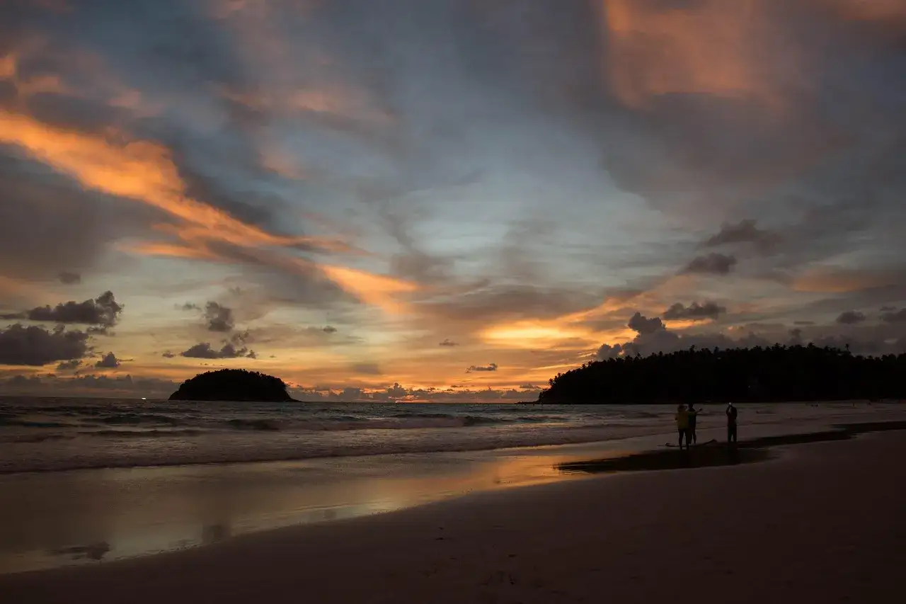 Zachód słońca na plaży na Phuket, z wyspą w oddali. Idealny moment, by zastanowić się, kiedy jechać na Phuket.