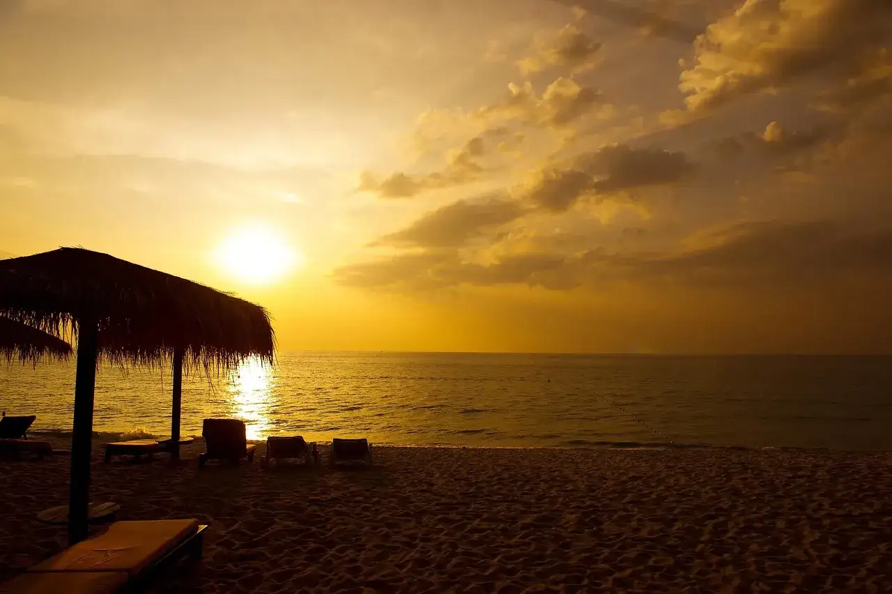 Zachód słońca na plaży na Phuket. Idealny czas, by pomyśleć, kiedy jechać na Phuket. Leżaki i parasol czekają.