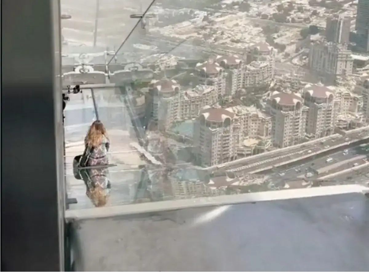 Widok z góry na Dubaj. Kobieta na szklanej platformie podziwia panoramę miasta.