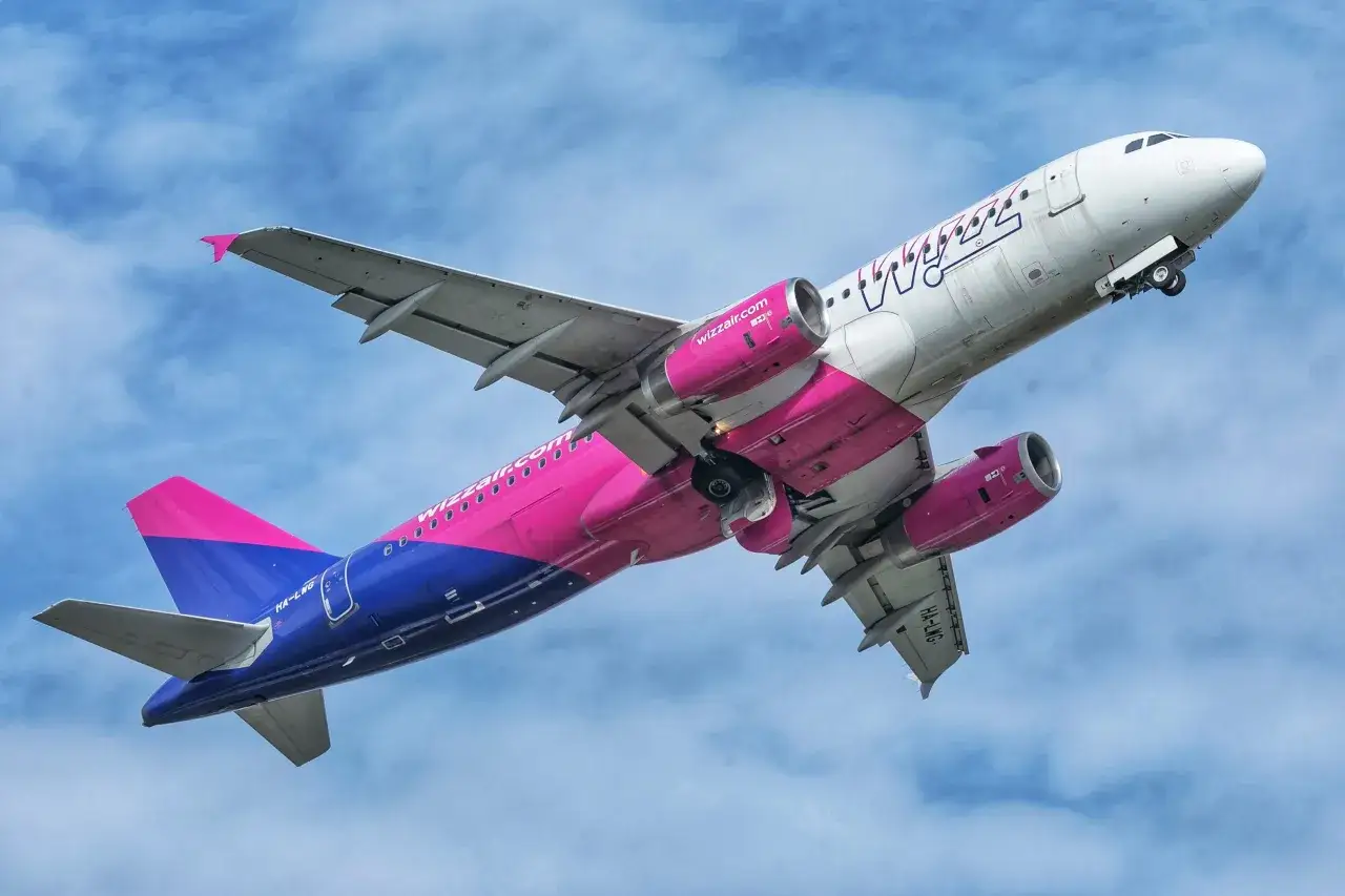 Samolot Wizz Air z różowymi silnikami i ogonem wznosi się na tle błękitnego nieba. Wizz Discount Club to program lojalnościowy linii.