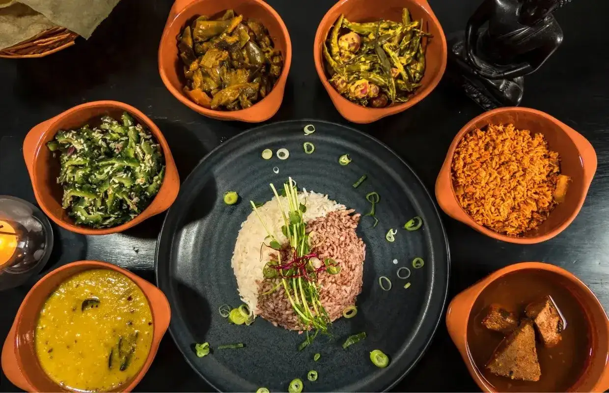 Kolorowe dania kuchni Sri Lanki: ryż, curry i dodatki w glinianych miseczkach.