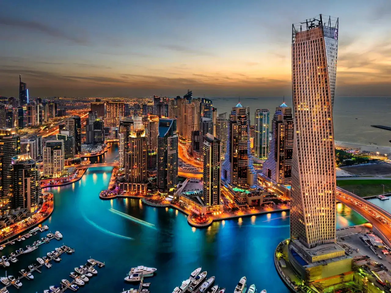 Wieżowce Dubaju oświetlone nocą, luksusowe jachty w marinie. Czy warto jechać do Dubaju? Widok zapiera dech w piersiach!